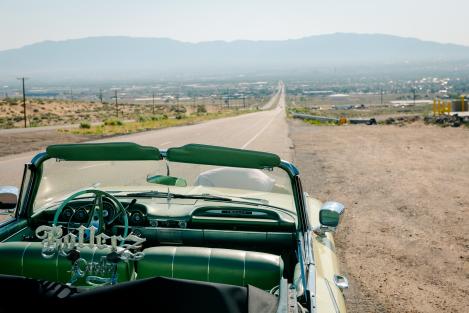 A lowrider sits on the side of the road of Central Ave. looking towards the Sandia Mountains.