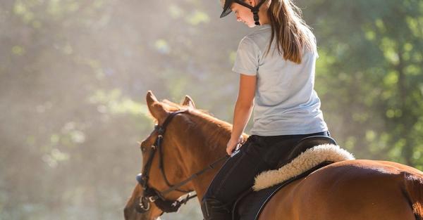 A young girl rides a horse at the Mackinac Island Community Equestrian Center