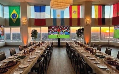 Two long tables line the dining room and are surrounded by flags from nations around the world and TV screens showing FIFA games.
