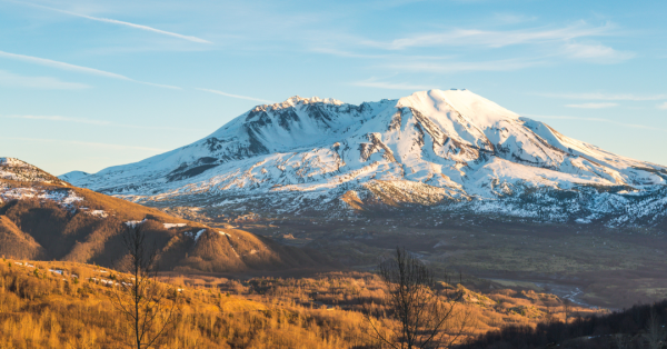 The snow-covered Mount St. Helens glistening as the sun begins to shine on it.