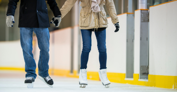 A couple of people holding hands as they ice skate at an ice skating rink in Vancouver, WA.