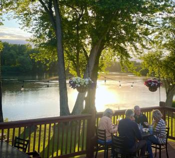 Picture of people dining on Penn's Tavern Patio with river flowing in the background
