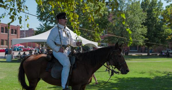 A civil war re-enactor sits upright on a horse while holding a sword at the Fort Smith National Historic Site.