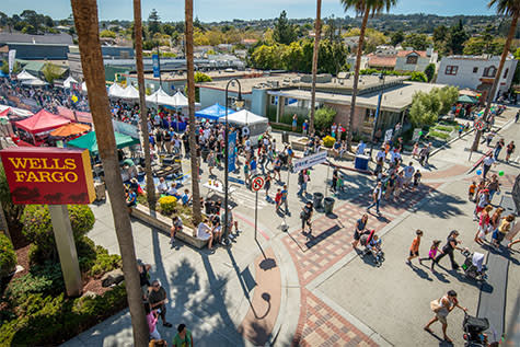 Millbrae Art and Wine Festival. People walking around festival. Palm trees and Wells Fargo sign in background.