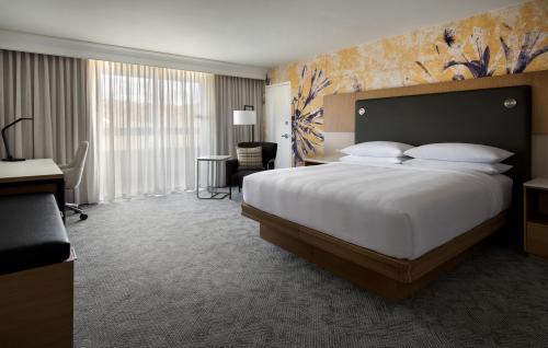 A hotel room with a king-sized bed. In the background is a yellow wall with flowers on it.