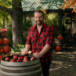 Ian Brownhill in autumn setting in front of barrel of apples