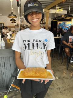 Female server at The Real Milk & Honey holds a plate of honey butter biscuits and smiles at the camera.