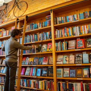 A wide of a person looking at a bookself at Maria's Bookstore