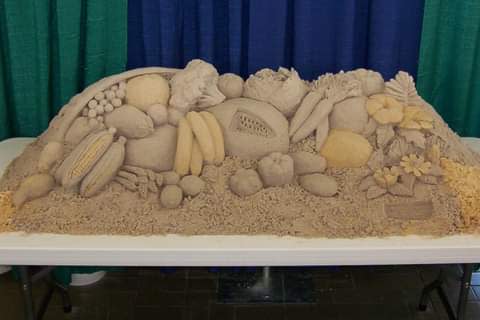 Sand sculpture on a table of a pile of vegetables