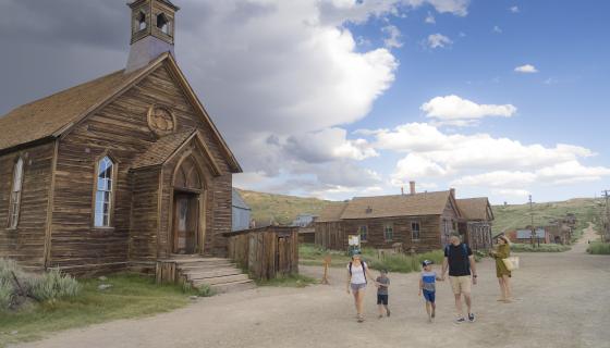 Family outside of the Methodist Church on a dirt road at Bodie State Historic Park