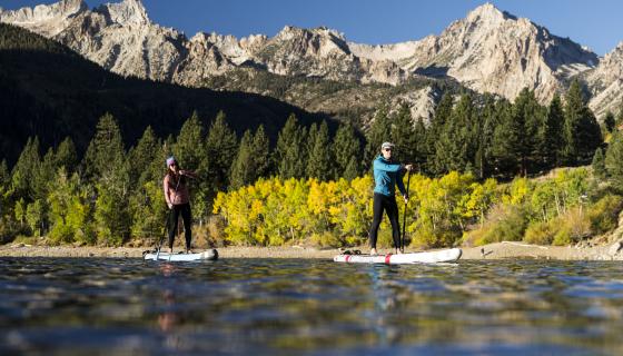 Two people paddle boarding on Lower Twin Lake near Bridgeport, CA with fall colors and snow-capped peaks