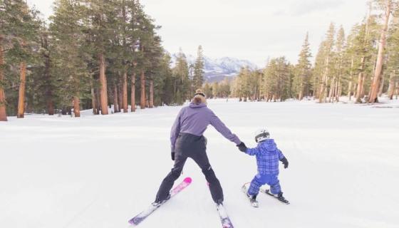 Mom and toddler holding hands while skiing at June Mountain