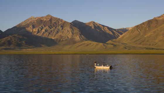 Angler on a boat on the waters of Crowley Lake with the Sierra Nevada mountains in the background