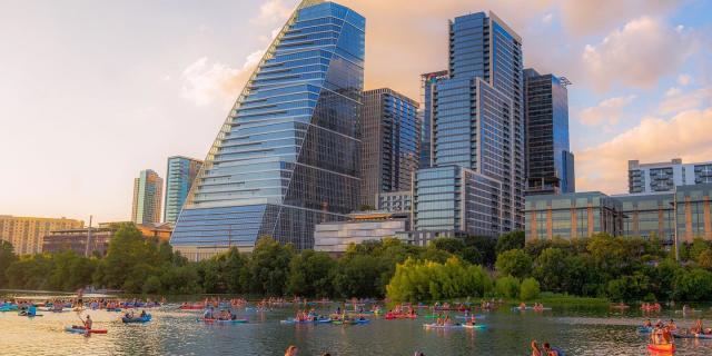 Image of people kayaking on Lady Bird Lake with the downtown skyline in the background.