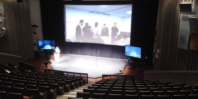 A view inside the Ontario Science Centre auditorium with theatre-style seating and big screen behind the stage