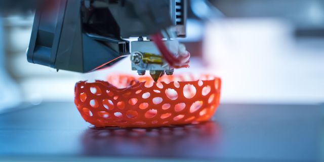 3D printer produces an orange object