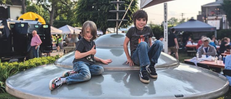 Two children sit on top of a UFO statue