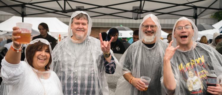 Attendees of an event smile at the camera while wearing rain ponchos