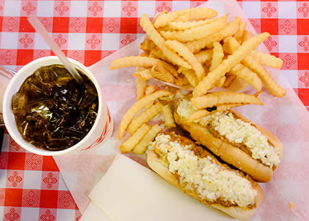 Two chili red hot dogs sit on a diner table with crispy French fries and a soda on the side at Jones Café.