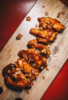 wooden plank with saucy bone-in wings featured at sugar whiskey sis moonshine bar in covington ky