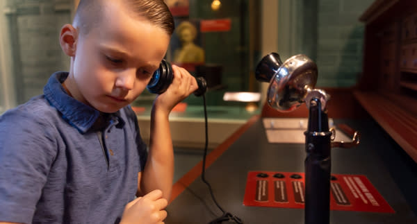 Boy listening to antique phone at Hershey Story Museum