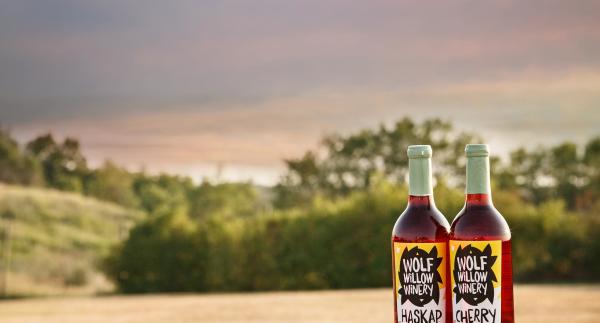 a bottle of cherry wine and haskap wine in front of a valley