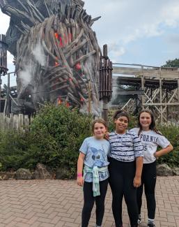 Three children standing in front of the Wicker Man ride at Alton Towers.