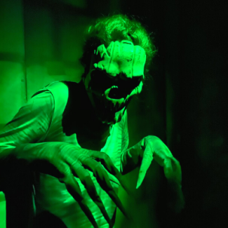 Scary figure illuminated by green light at FrightWorks