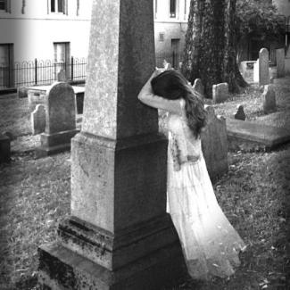 Black and white image of a girl crying leaning against a tombstone on the Knoxville Walking Tours Cemetary