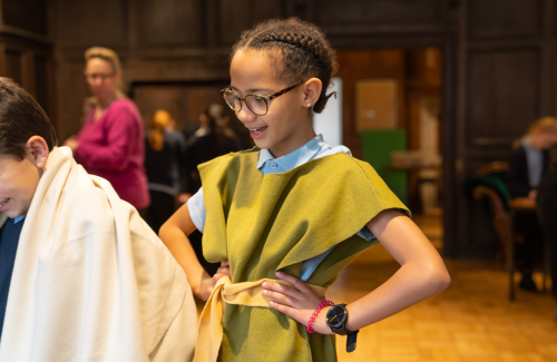 A child in medieval peasant costume smiling with her hands on her hips