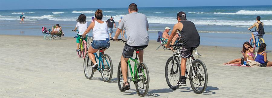 With plenty of elbow room, a family easily bicycles along the hard packed sands of Daytona Beach