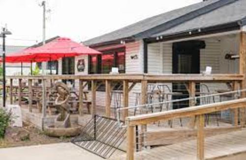 A white restaurant with an outdoor patio and a red umbrella