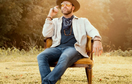 Singer Drake White poses for a photo outside while sitting in a chair