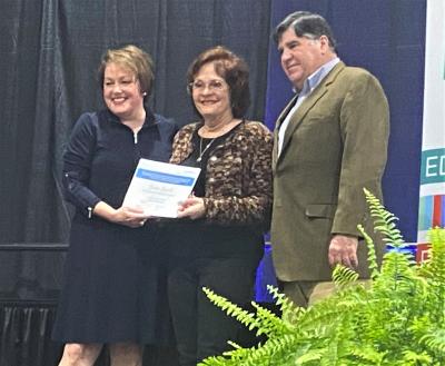 Louise Lovich receives Certified Travel Specialist certificate from LTA President and CEO Jill Kidder and Restaurateur Dickie Brennan at the 2022 Louey Awards.