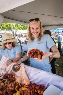 A woman holds a platter of boiled crawfish, classic festival fare