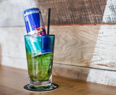 Green cocktail with red bull filled upside down in drink