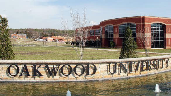 Oakwood University campus in Huntsville, featuring a stone sign and fountain in front of a large brick building.