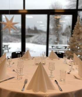 Dekket bord med julestjerner og juletre i vinduet og snø på utsiden