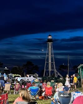 crowd sitting near George Core Park waiting for fireworks with lighthouse in the background