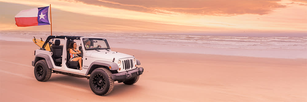 Two people in a jeep on the beach.