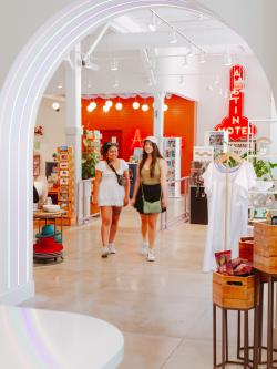 Two women walking through the bright and colorful Austin Visitor Center while having a conversation.