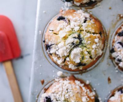 Tin of blueberry muffins topped with powdered sugar next to spatula at Cherbourg Bakery