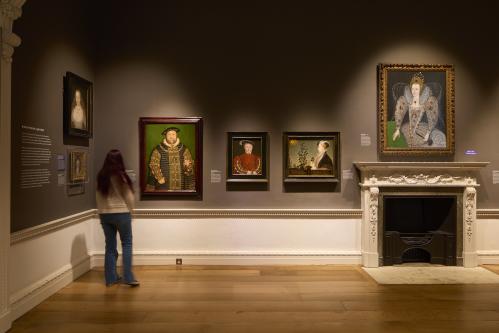 A person with their back to the camera observing paintings in an art gallery