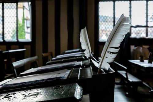 Old fashioned wooden school desks with quills in inkwells in a Tudor schoolroom
