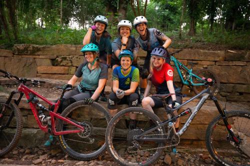 A group of women gathered on a trail posing for a picture with their bikes
