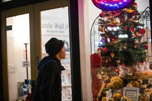 Man looks through store-front at Christmas tree and gifts in Bowling Green, KY store.