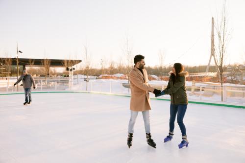 A couple holding hands while skating on the Riverside Crossing Park ice skating rink