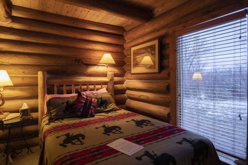 Cozy cabin interior with bed and a view, Vee Bar Guest Ranch, Laramie, Wyoming