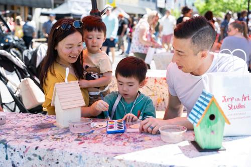 A young family painting birdhouses at the Kidscreate Station at Arts In Bloom.