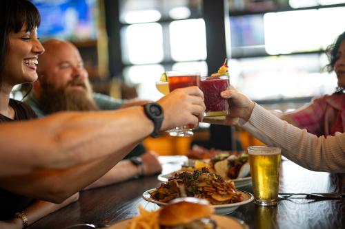 Three young adults cheers-ing their glasses together in celebration